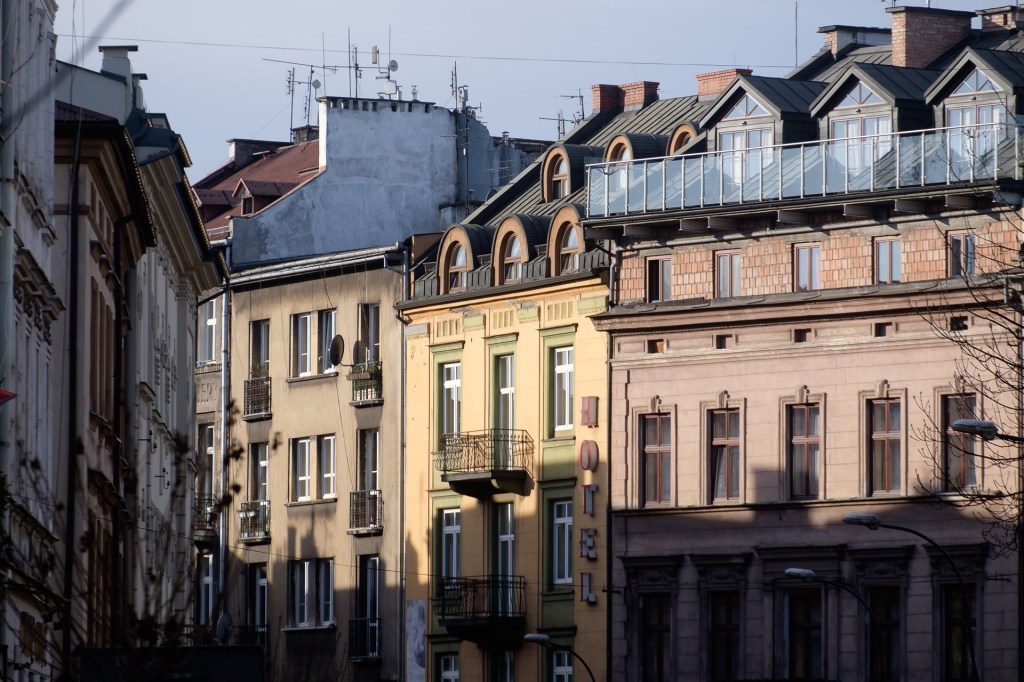 Utsikt över byggnader i Kraków med synliga fasader och en hotellskylt.