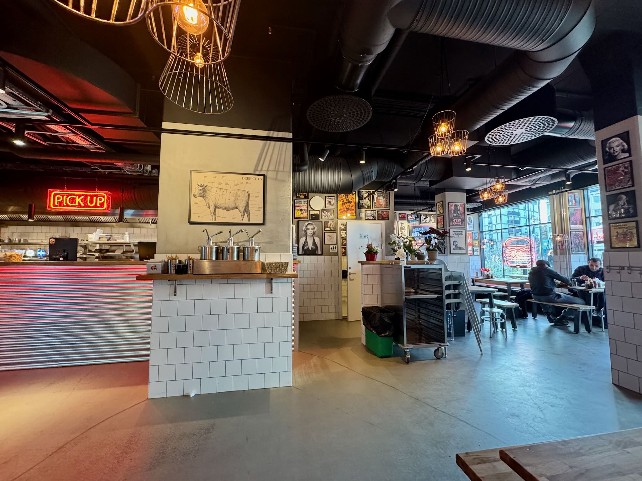 Inre design av Andys Burgers i Malmö med en modern och trendig atmosfär, inklusive en bar med redskap och en 'PICK UP'-skylt.
